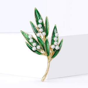 Elegant gold tree leaf brooch with green enamel and white pearls on white background