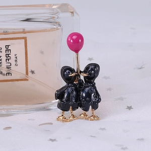 Detail of creative enamel duck brooch featuring two black ducks holding a pink balloon