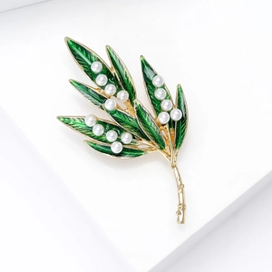 Elegant gold bamboo leaf brooch with green enamel and white pearls on white background