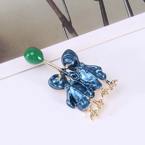 Detailed close-up of enamel duck brooch with blue hooded coats holding a green balloon