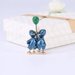 Detail of enamel duck pins with a green balloon placed against a textured gift box