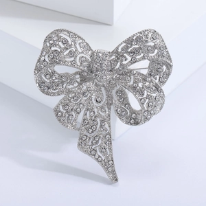 Close-up of sparkling silver bow brooch featuring intricate hollow metal and rhinestones