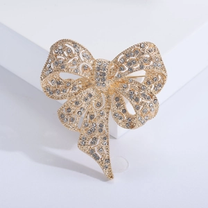Close-up of golden bow brooch featuring intricate hollow metal work and sparkling rhinestones