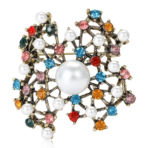 Vintage style gold-plated brooch with pearls and colorful rhinestones on white background