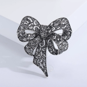 Vintage rhinestone bow brooch in antique silver finish with detailed hollow filigree design