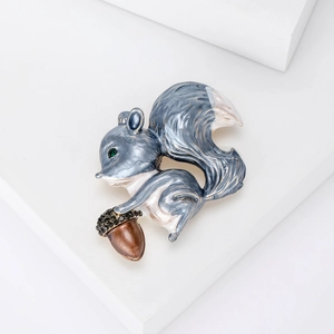Broche écureuil créative avec finition bleue et gemme verte sur présentoir blanc