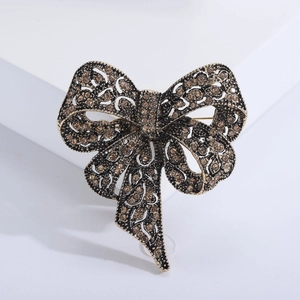 Macro detail of vintage bronze bow brooch with amber rhinestones and filigree texture