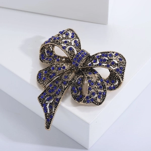 Vintage gold bow brooch with deep blue rhinestones and intricate hollow carving