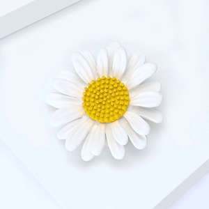Détail macro d'une broche marguerite aux pétales blancs et centre jaune texturé