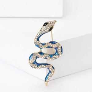 Détail d'une broche serpent dorée avec émail bleu et strass brillants incrustés