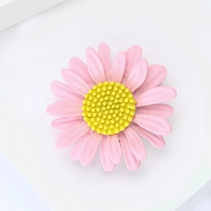 Détail macro d'une broche marguerite en émail rose avec un cœur jaune texturé
