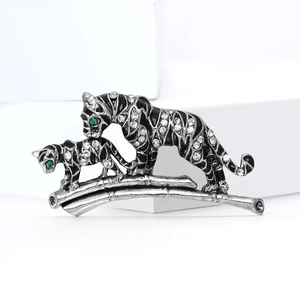 Sparkling tiger family brooch with crystals and green eyes on a bamboo branch