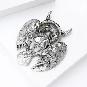Vintage silver owl brooch with spread wings and crystal inlay against minimalist white decor