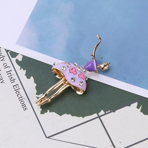 Détail de la broche ballerine avec robe en émail violet et cristaux sur fond de livre