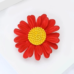 Broche marguerite créative en émail avec pétales rouges sur un fond blanc épuré