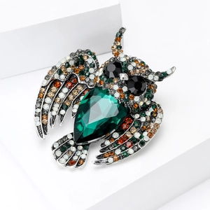 Detailed close-up of vintage owl brooch featuring emerald green gem and colorful rhinestones