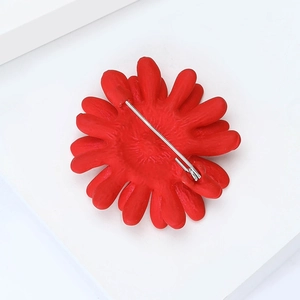 Vue détaillée de la broche fleur de marguerite rouge avec émail mat et épingle de sûreté