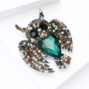 Macro view of vintage owl brooch with emerald teardrop stone and colorful rhinestones