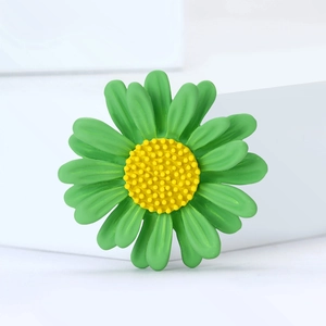 Broche marguerite vert et jaune avec finition mate sur fond blanc minimaliste