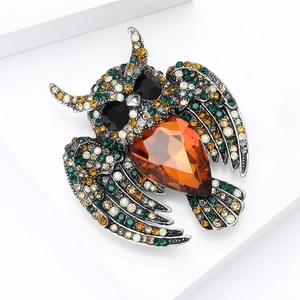 Macro shot of vintage owl brooch with orange teardrop gemstone and multicolored crystals