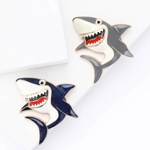 Cute blue and grey enamel shark brooches displayed on minimalist white props