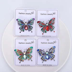 Dettaglio di quattro spille a farfalla in smalto colorato con strass su scheda display