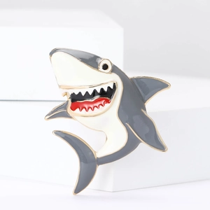 Detail of shark enamel pin with gold metal edges on a geometric white display base