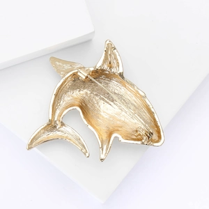 Detailed macro view showing the brushed metal texture and back pin of a gold shark brooch