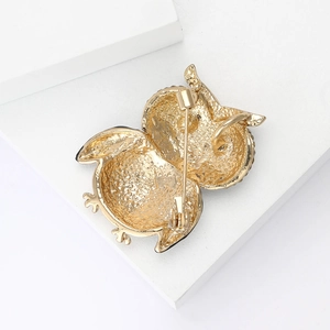 Macro shot of owl brooch back with textured gold metal and secure safety pin closure