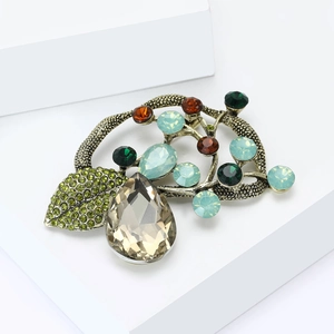Macro shot of vintage floral brooch with emerald and amber crystals on antique gold base