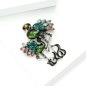 Detailed close-up of flamingo bird brooch with green enamel and sparkling crystals