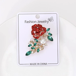 Detailed macro view of rose crystal brooch with red rhinestones and pearl on display card