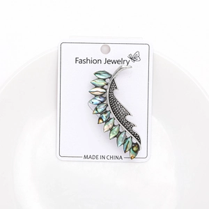 Detailed close-up of leaf-shaped brooch with iridescent abalone shell on silver base