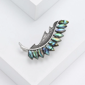 Vintage silver feather brooch with iridescent abalone shell inlays on white pedestal