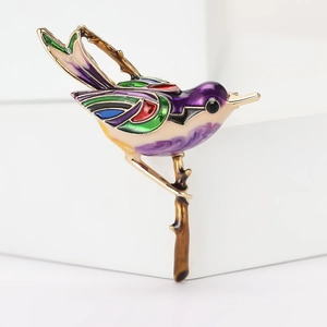 Detailed macro view of colorful enamel bird brooch resting on a bronze branch
