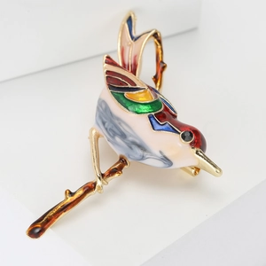 Elegant bird brooch in enamel and gold alloy finish perched on a delicate golden branch