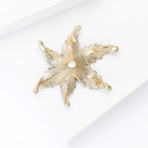 Detail of leaf brooch back showing golden hammered metal texture and safety pin clasp