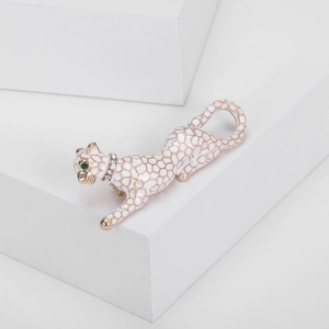 Detailed macro view of white enamel leopard brooch with gold-tone spots and green gem eyes