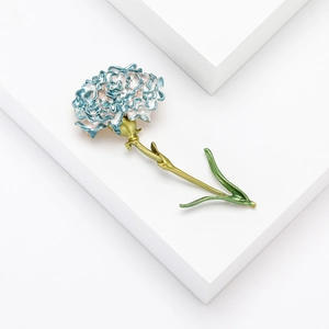 Dettaglio della spilla a garofano in smalto blu e bianco con stelo verde su base moderna