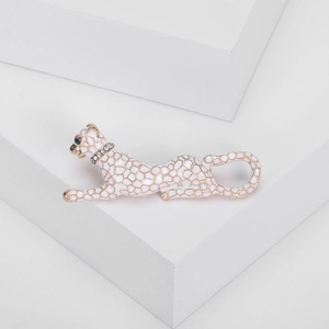 Macro detail of white enamel leopard brooch with golden honeycomb patterns and green gemstone eyes