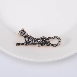 Detailed view of leopard brooch with black enamel spots, gold edges, and green stone eyes