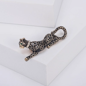 Detail of leopard brooch featuring black enamel with gold trim and green gemstone eyes