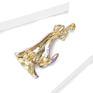 Detailed close-up of a vintage golden brooch with purple enamel on a white prop