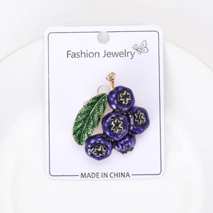 Close-up of creative blueberry brooch with deep purple berries and green leaf on jewelry card