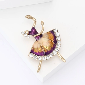 Dettaglio di una spilla da ballerina con smalto viola e strass lucidi su sfondo bianco