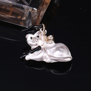 Macro detail of cat brooch with graduation cap and scroll in pearl white enamel