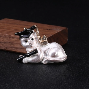 Macro shot of an enamel graduation cat brooch with pearl finish and gold metal tassel
