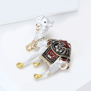 Detail view of white enamel camel brooch with golden chains and sparkling rhinestones