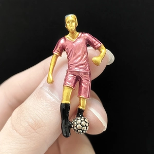 Detail of creative football player brooch with red jersey and golden finish accents