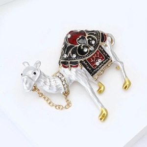 Macro detail of camel brooch with white enamel, rhinestones and golden chains